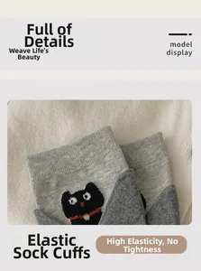 Detail of grey knitted sock with black cat embroidery and elastic cuff for women