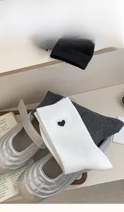 Detail of grey and white knitted socks with heart embroidery next to silver Mary Jane shoes