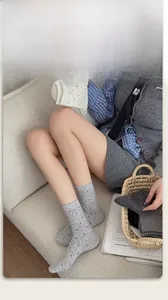 Detailed knit texture of grey polka dot socks shown in a cozy home setting with a sofa