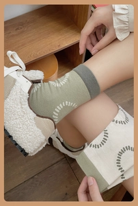 Close-up of grey-green and beige patchwork cotton socks with white circle patterns