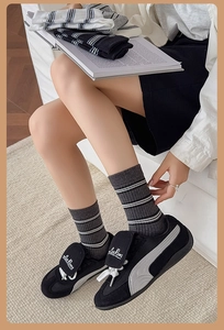 Detail of dark grey crew socks featuring triple white stripes and ribbed knit texture