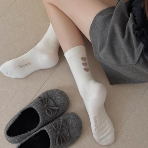 White crew socks with Tom's family embroidery and hearts, worn with grey felt slippers