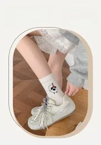 Detail of white knit crew socks featuring a cute 3D cartoon sheep and pearl shoelaces