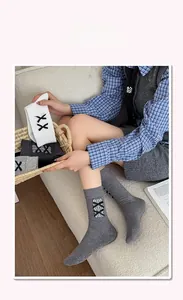 Détail de chaussettes mi-mollet douces avec nœuds noirs et rubans lacés en tons gris