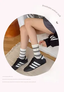 Detail of cream striped cotton socks with rectangular tag shown with sneakers