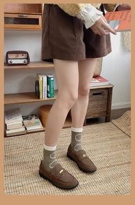 Detail showing olive green crew socks with white wave patterns and brown loafers