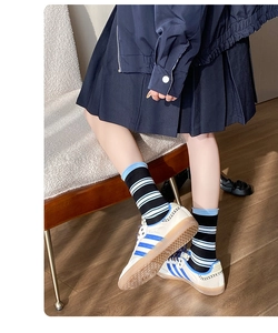 Dettaglio di calze a righe nere e blu abbinate a sneaker classiche sportive