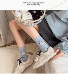 Detail of light blue cotton socks with cute cartoon dog embroidery and red polka dots