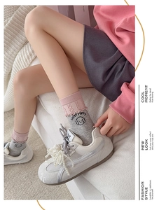 Detail of pink and gray ruffled socks with lucky puppy pattern and pearl sneakers