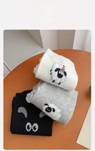 Close-up of knit crew socks in black, white, and grey with cute 3D cartoon sheep details