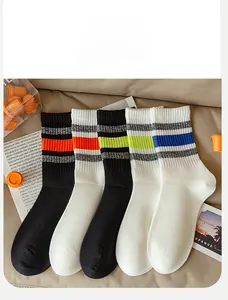 Macro shot of five pairs of ribbed cotton socks with colorful athletic stripes on a tan fabric