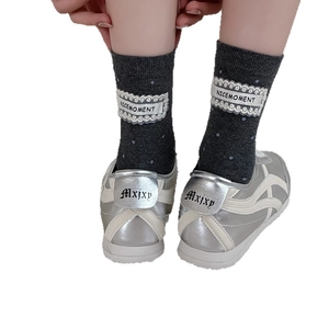 Polka dot crew socks with lace trim and silver sneakers in a back view pose