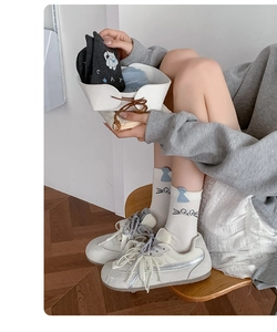 Close-up of white crew socks with cute cat patterns and pearl-decorated sneakers