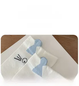 Detail of white cotton sock featuring a blue 3D ear design and cute cartoon cat face print
