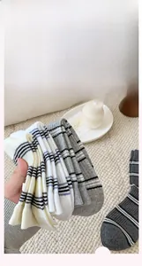 Detail of striped cotton crew socks set in beige, white, and grey with ribbed knit texture