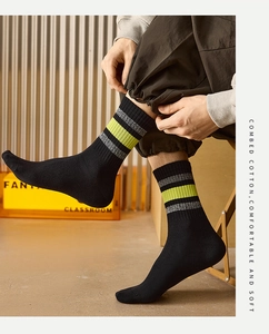 Detail of combed cotton crew socks featuring grey and neon green stripes on black fabric