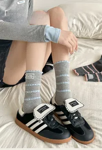 Detailed view of grey cotton crew socks with blue lace trim and side fabric label