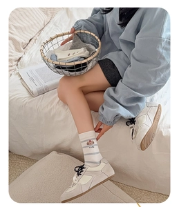 Detail of white striped socks with Lucky bear print paired with sneakers on a bed