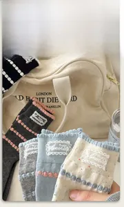 Detail of soft cotton crew socks with ruffled cuffs and lace logo patches in various colors