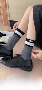 Detail of grey ribbed cotton socks with stripe cuffs and brand label in black shoes