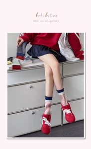 Detail of red and white striped cotton socks with navy blue ribbed cuffs on a model