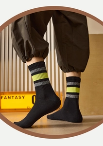 Close-up of black cotton crew socks featuring neon green stripes and ribbed knit texture