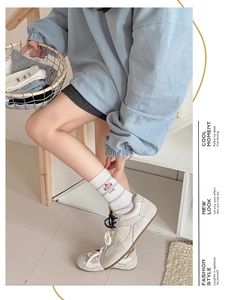 Detail of white crew socks with blue stripes, brown bear pattern and Lucky text embroidery