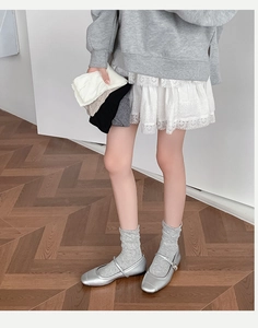 Detail of light gray ballet style socks with silver Mary Jane shoes and lace skirt