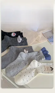Detail of designer crew socks with bow, polka dots, and ruffles in gray and white