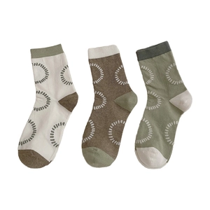 Three pairs of mid-calf socks with dotted circle patterns in neutral color combinations