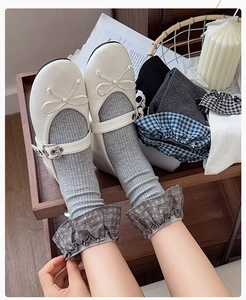 Close-up of grey knit mid-calf socks with plaid ruffle trim and Mary Jane shoes