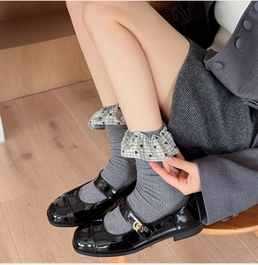 Detail of grey socks featuring plaid lace ruffles and heart patterns with Mary Jane shoes