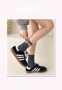 Close-up of dark grey ribbed mid-calf socks featuring cute 3D cartoon embroidery details