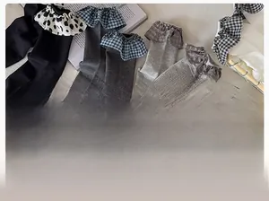 Close-up of ribbed cotton socks with plaid ruffled lace trim in gray and black