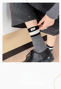 Detail of grey ribbed mid-calf socks with striped trim and white woven min min label