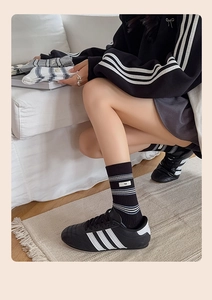 Close-up of black and white striped knit socks with egg logo label on a cozy background