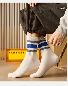 Detail of white cotton crew socks featuring blue and grey stripes with ribbed cuffs