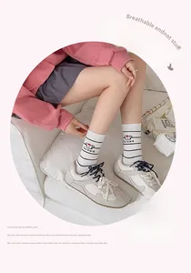 Close-up of white mid-calf socks with black stripes and a cute bear design on the side