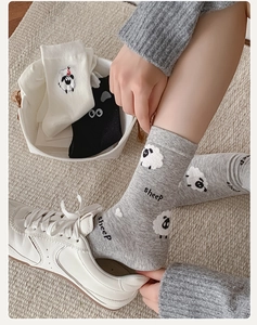 Close-up of sheep pattern crew socks in grey, white, and black cotton blend knit