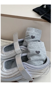 Detail of silver Mary Jane shoes with velcro straps and heart pattern mid-tube socks