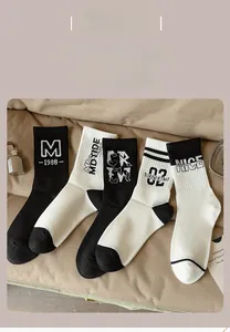 Flat lay of five mid-calf cotton socks with letter patterns on a soft fabric background