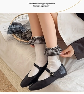 Detail of white cotton crew socks with black and white plaid ruffled cuffs for women