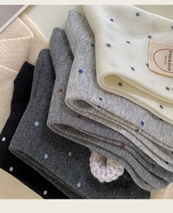 Detailed close-up of multi-color polka dot knit socks in grey and cream cotton blend