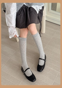 Detailed view of light grey ribbed knit socks paired with black Mary Jane shoes