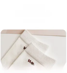 Detail of white knit socks showing elastic cuffs and fine texture with brown lettering