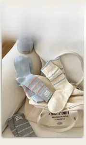 Close-up of pastel cotton crew socks with soft pom-poms and ribbed cuffs detail