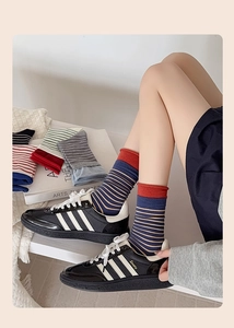 Close-up of knitted striped mid-calf socks in various colors with rolled cuff detailing