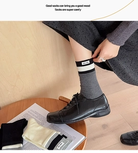Close-up of gray ribbed knit mid-tube socks with stripe design and fabric labels