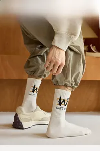 Close-up of crew athletic socks with WAT'S UP lettering paired with green cargo pants