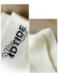 Detailed close-up of ribbed cuffs and reinforced heels on white lettered cotton socks